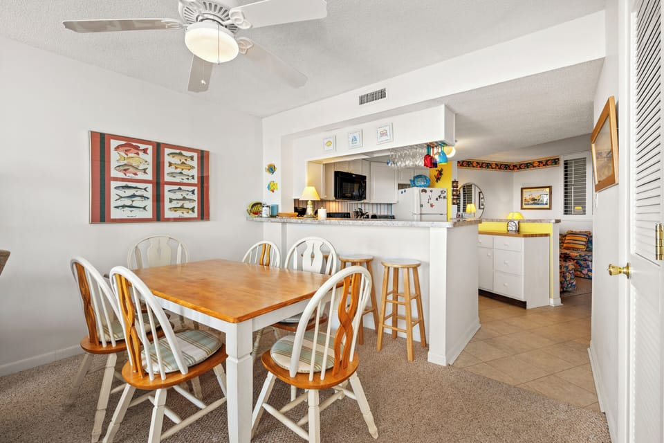 Your open kitchen and dining space blends comfort with coastal charm, featuring a breakfast bar and cheerful touches perfect for family meals.