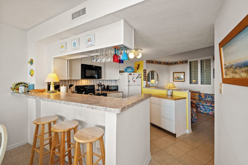 Your fully equipped kitchen features granite counters, breakfast bar seating, and everything needed for home-cooked meals during your beach getaway.