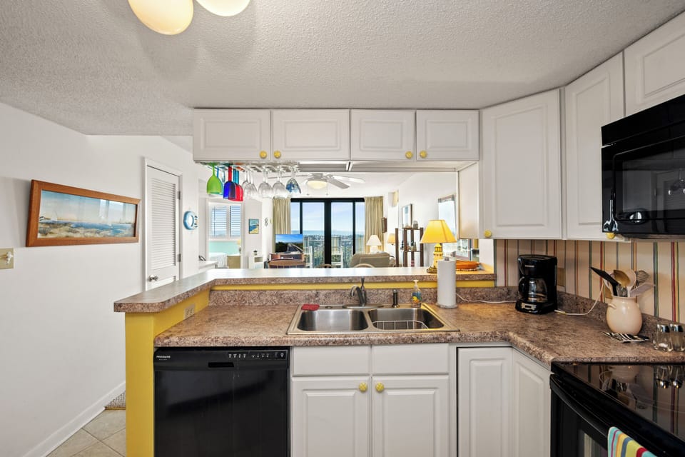 Cook with ocean views from your fully equipped kitchen featuring granite countertops, modern appliances, and cheerful yellow accents throughout.