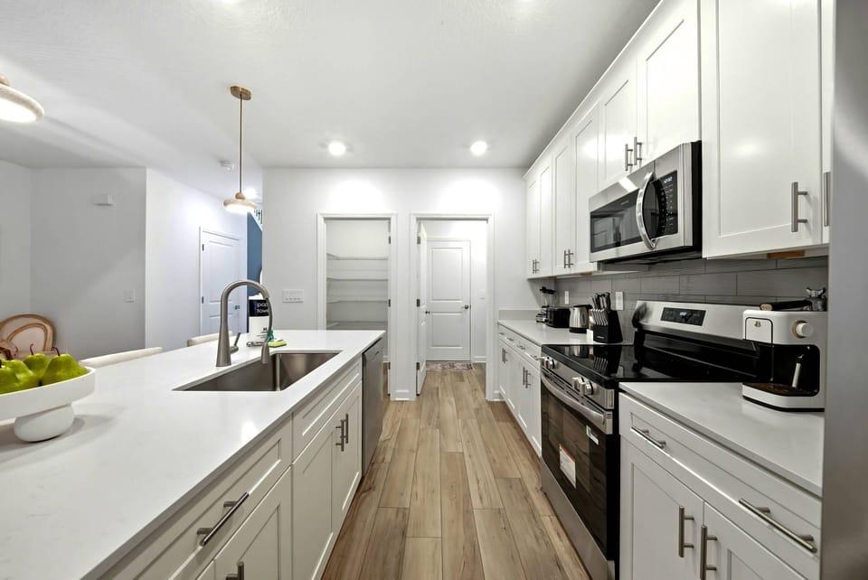 Experience our modern kitchen featuring stylish white cabinetry and a roomy island perfect for meal prep or casual dining. The inviting wood floors and stainless steel appliances create a bright and functional cooking environment.
