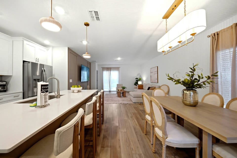 Enjoy a bright dining area featuring a beautiful wooden table with elegant cream chairs. The modern kitchen offers sleek finishes and a spacious island for your culinary creativity, all highlighted by stylish pendant lighting.