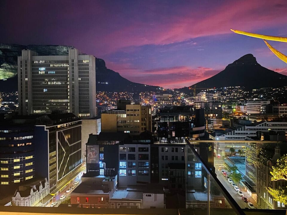Sunset City Views: Beautiful skyline with glowing city lights and mountain views at sunset. Rich colors fill the sky, creating a calm and scenic setting, perfect for evening stays and photos.