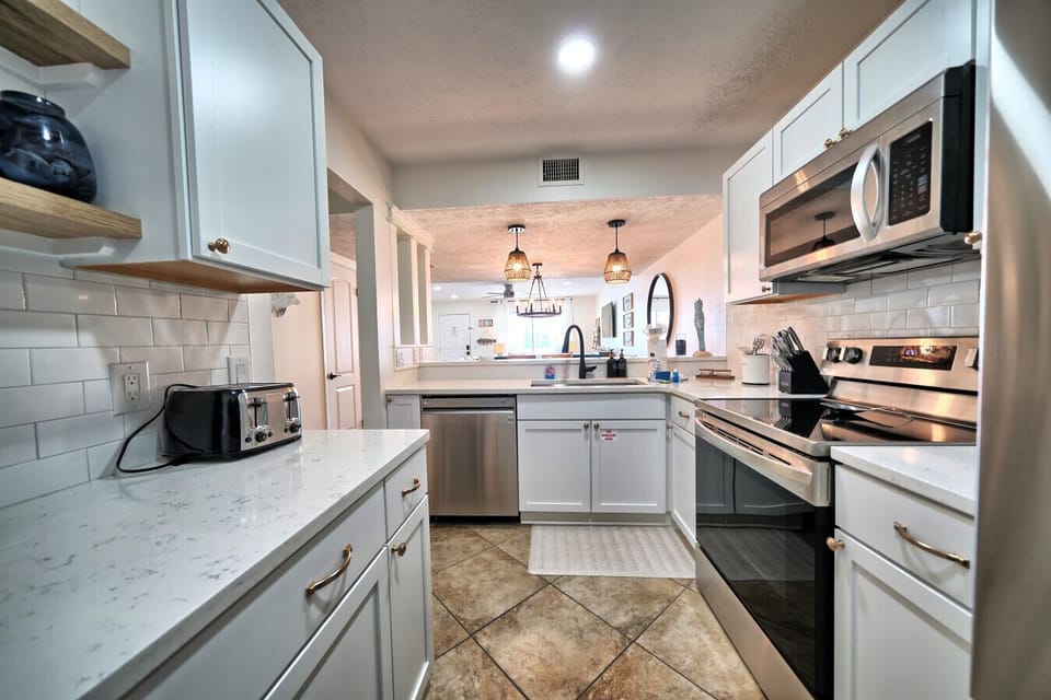 Your culinary haven awaits with this fully equipped kitchen, featuring stainless steel appliances, pristine quartz countertops, and sleek white cabinetry. Prepare delicious meals with ease, making your beach retreat truly exceptional.