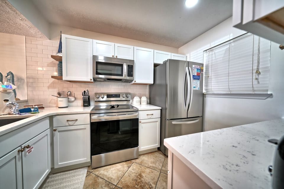 This fully equipped kitchen features sleek stainless steel appliances, pristine white cabinetry, and ample quartz counter space. Prepare delicious meals with ease, making your beachside retreat truly feel like home.