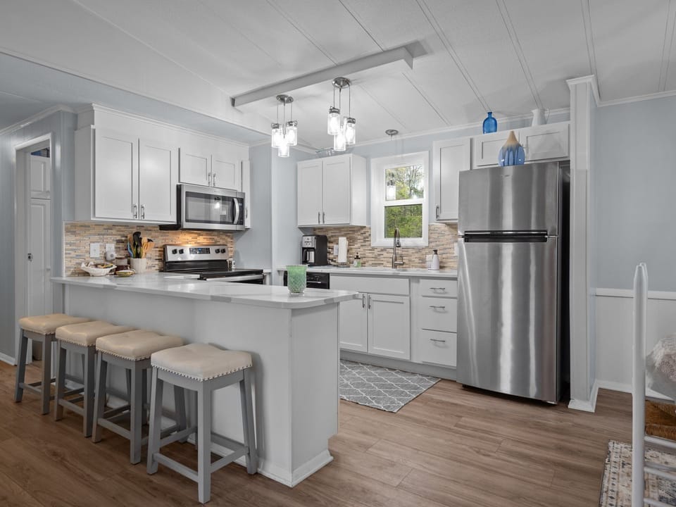 Your spacious kitchen invites culinary adventures with stainless steel appliances, crisp white cabinetry, and a breakfast bar perfect for morning coffee.