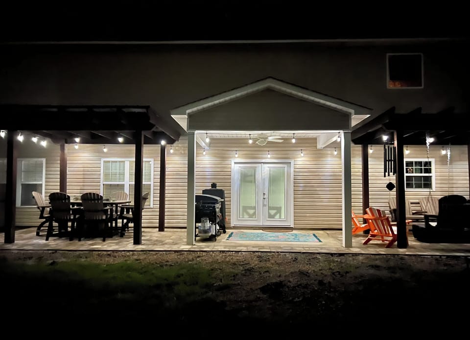 Evening exterior view showcasing the property's welcoming facade with outdoor seating areas and atmospheric string lighting.