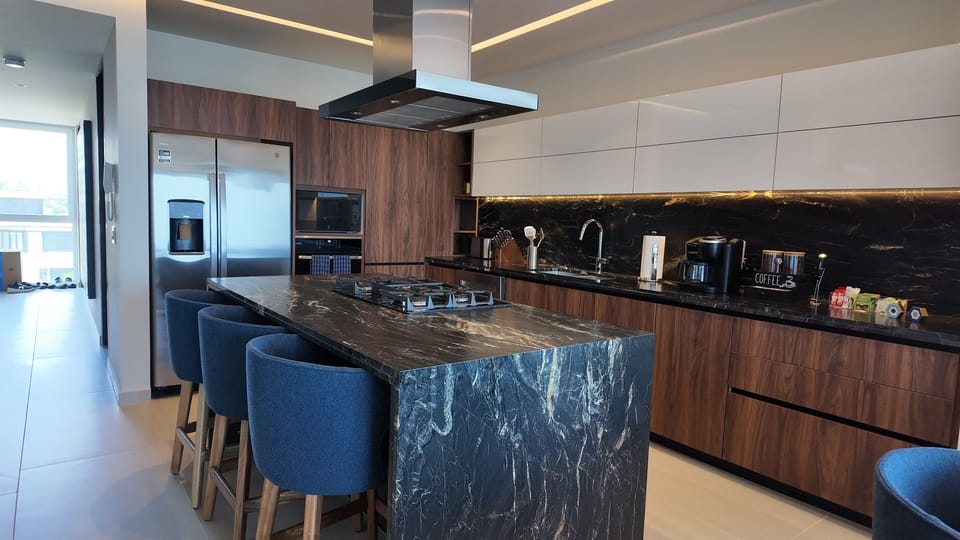 A fully loaded chef's kitchen — 6-burner gas stove, oven, fridge, microwave, island seating for 3, pots & pans, and a stocked spice rack. Everything you need, nothing you don't.