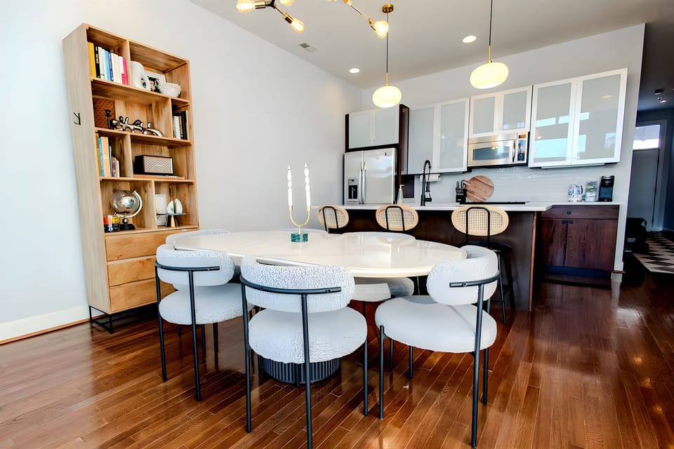 Gather around the large oval dining table for a family feast under the glow of modern pendant lighting. The light wood floors and white cabinetry keep the space feeling airy and clean.