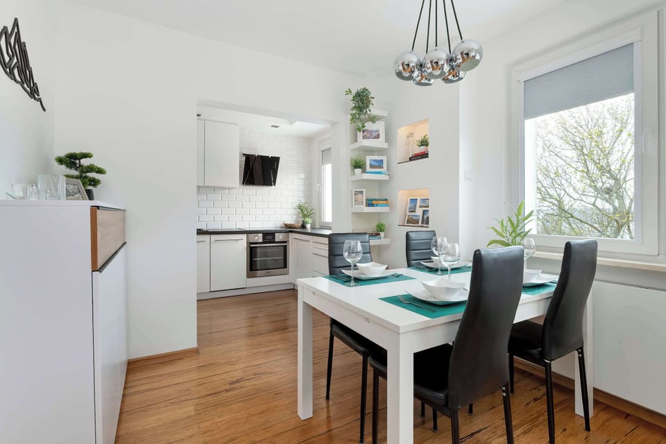 A dining area next to a compact kitchenette, set near a window. Practical and neatly arranged.