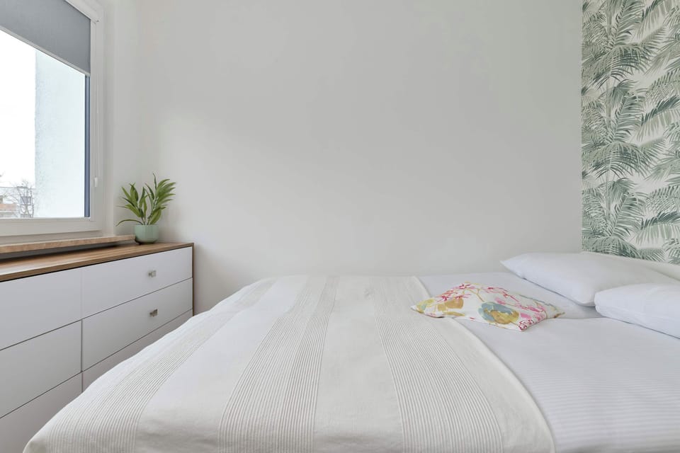 A cozy bedroom with a double bed and light decor. Soft tones create a calm atmosphere.
