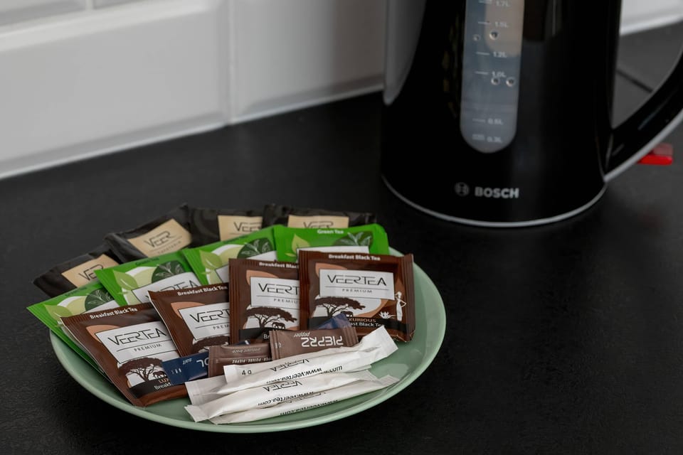 An electric kettle with neatly arranged coffee and tea sachets on a tray. A practical and welcoming setup for making a hot drink.