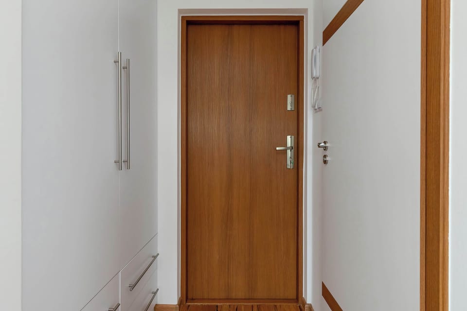 An entry hallway with a wooden door and white walls. Minimalist and tidy.