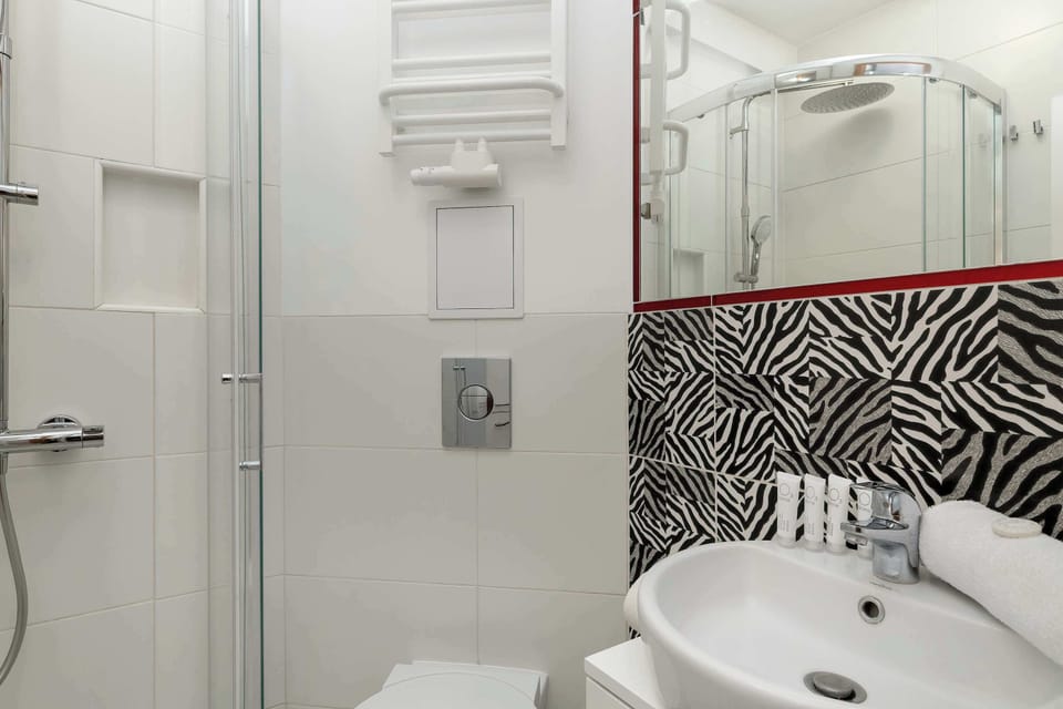 A bathroom detail with a sink, mirror, and patterned tiles. Bright and well-kept.