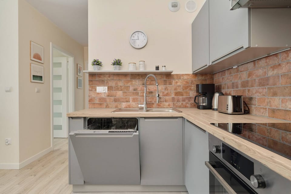 Fully equipped kitchen featuring a modern oven, microwave, and brick-style accents.


