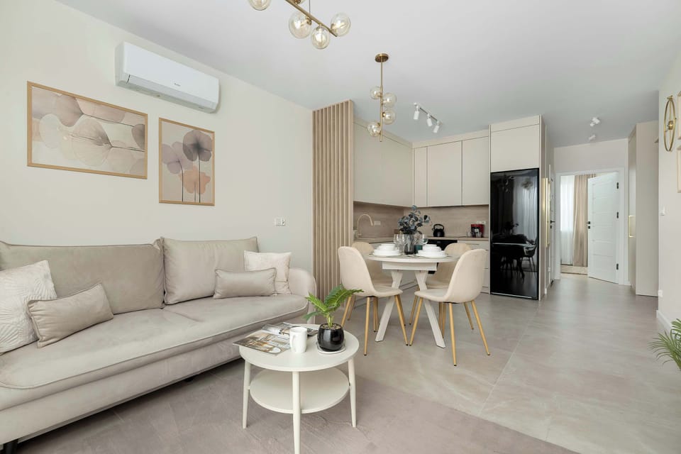 A bright living space seamlessly integrates a comfy couch with a dining table and chairs. A large window provides an open feel, and the wall art adds a hint of elegance to the shared room.