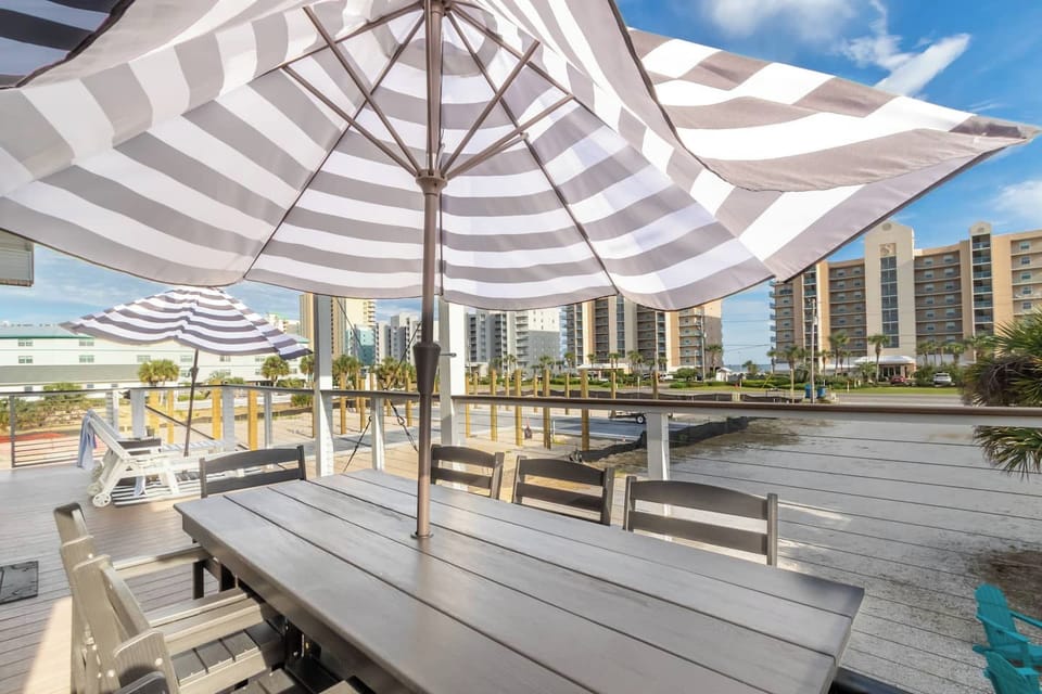 Sunny coastal deck with dining and loungers, water views near the beach.