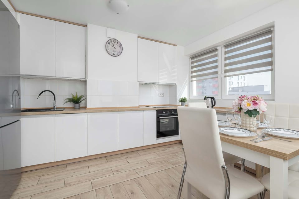 The kitchenette is well-lit by a wide window equipped with adjustable grey blinds.