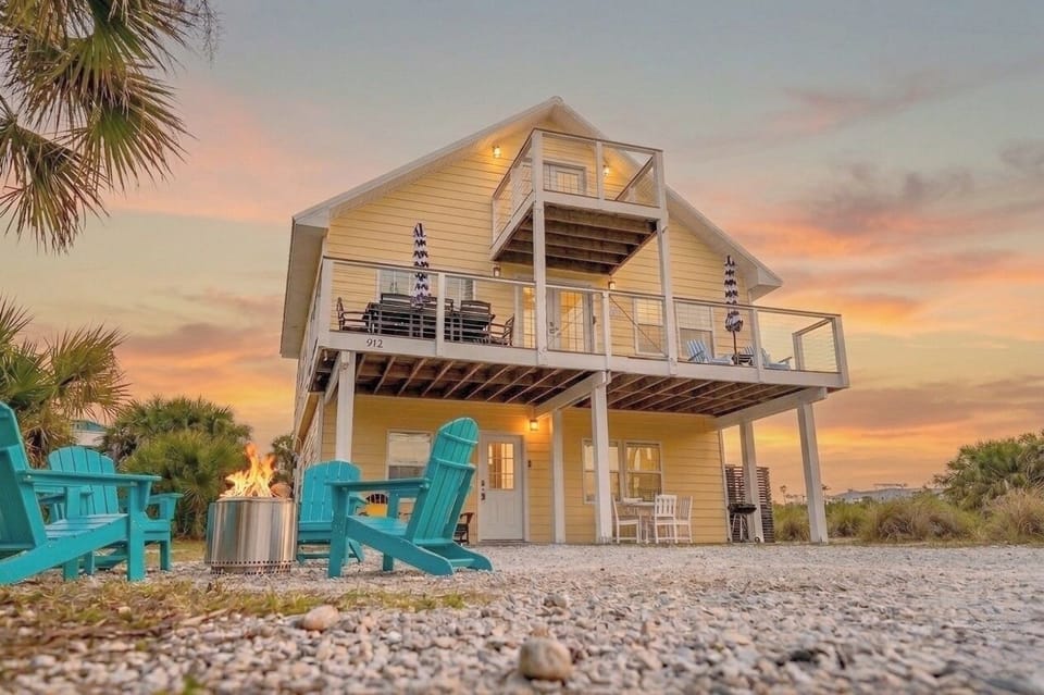 Elevated beach retreat with fire pit, wraparound deck, sunset views.