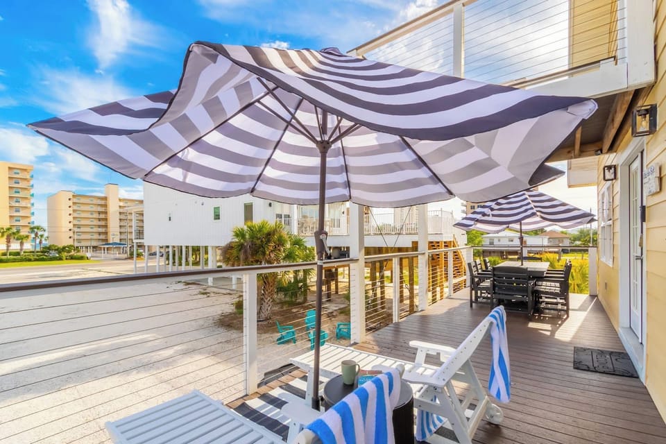 Sunny coastal deck with dining, loungers & shade umbrellas
