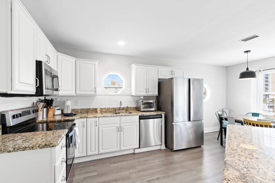 Bright kitchen with granite, stainless appliances, and island seating