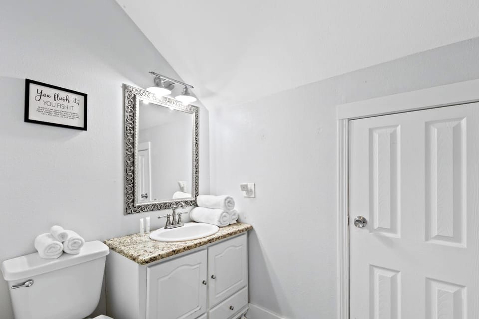 Bright, spotless bath with granite vanity, luxe mirror, and fresh towels.