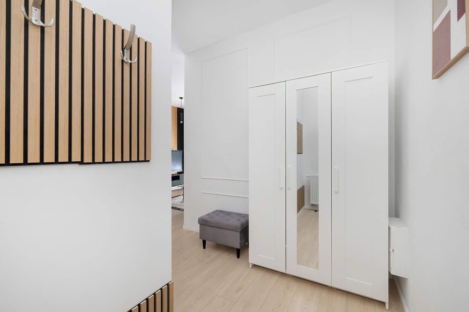 A hallway with wardrobes and a large mirror. The space is functional and designed for storage.