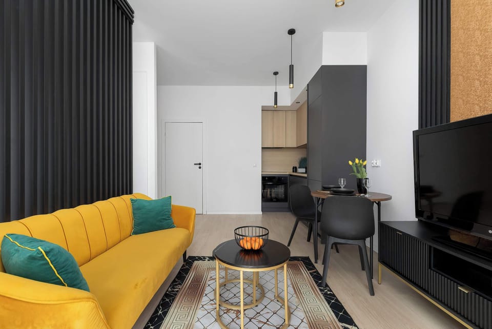 Another angle of the living room highlighting the seating area and TV wall. The combination of warm accents and clean lines creates a balanced design.
