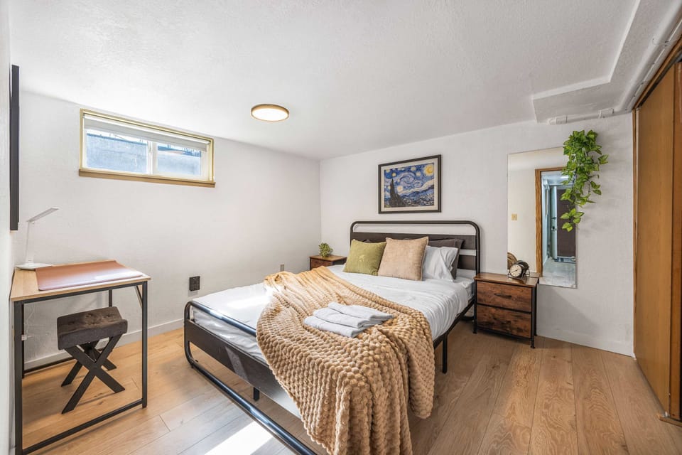 Bright bedroom with natural light, a work desk, and a cozy, welcoming feel.