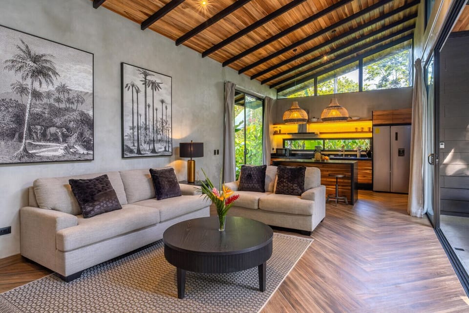 Bright living and kitchen area with large windows and jungle views, creating a seamless indoor-outdoor experience.
