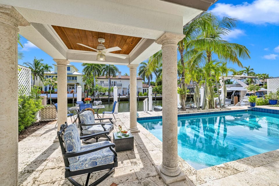 Waterfront patio offering a shaded dining table, lounge seating and direct pool access