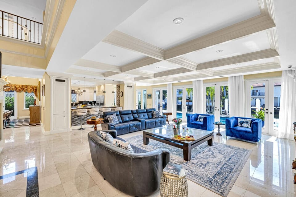 Contemporary lounge featuring ample leather sofas, a designer palette and glass-front doors opening to the pool