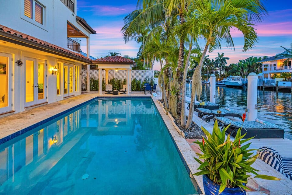 Resort-style pool area featuring a shaded dining space and ample waterfront loungers ideal for families