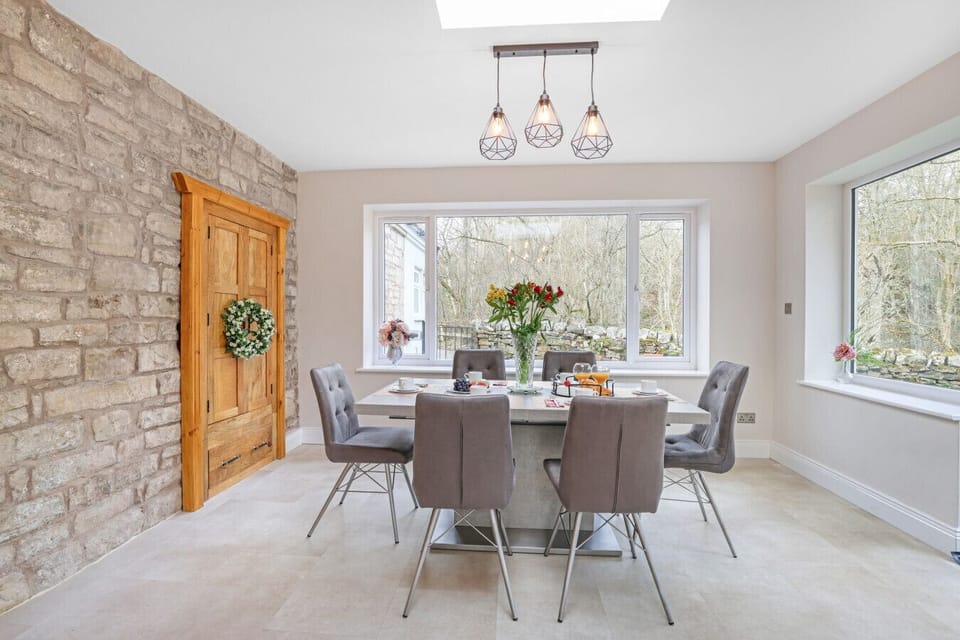 A sleek, modern dining set sits within a bright room featuring a rustic stone accent wall.