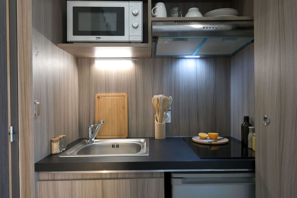 Modern kitchenette with wood finishes and integrated appliances for independent stays.