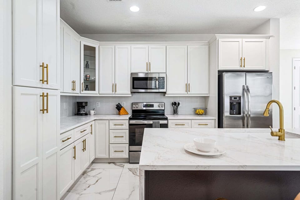 Cook with ease in a bright kitchen w/ stainless appliances, white cabinetry & clean finishes