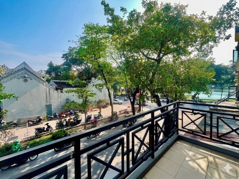 Private balcony with partial view of Hồ Hoàn Kiếm and peaceful street below
