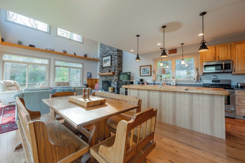 Cook in style in this modern, chef-ready kitchen featuring a massive wood island and stainless appliances. The open-concept flow leads to a cozy banquet dining area, perfect for family feasts with a view of the forest.