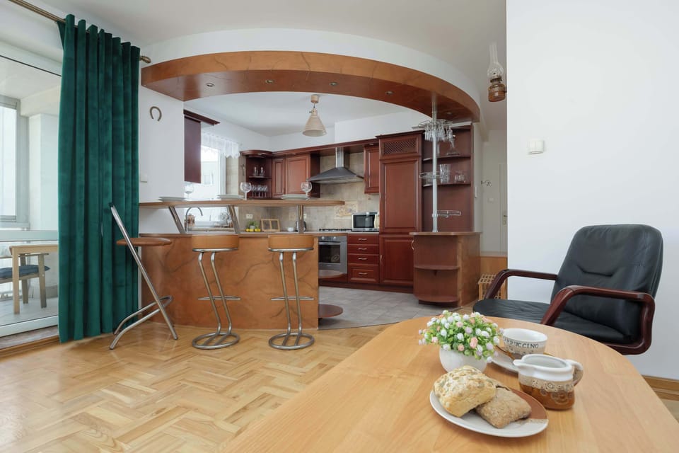 Another angle of the open kitchen and living room, highlighting the bar counter and polished wood finishes.