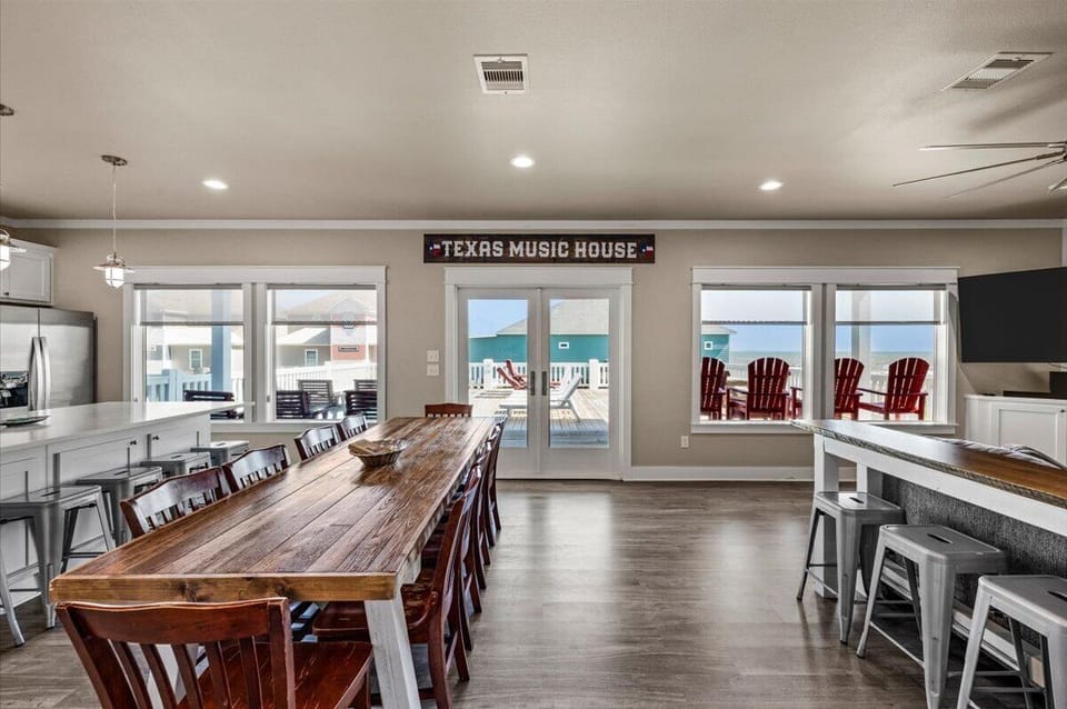 Open dining space with long table and access to outdoor deck in Port Bolivar coastal home