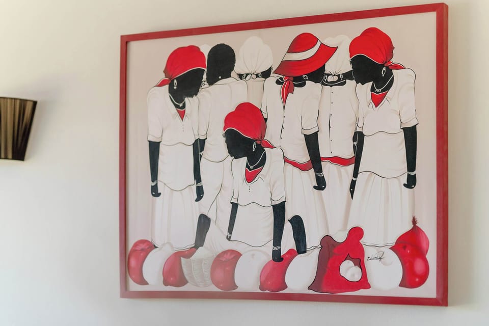 A vibrant piece of wall art featuring stylized figures in red and black serves as a bold focal point. The painting is mounted on a clean, light-colored wall to draw the eye.