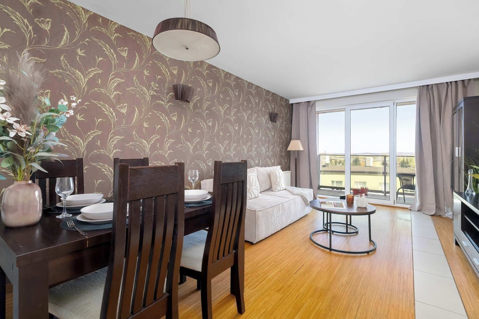 A spacious living room featuring a large sofa, a chic coffee table, and a large window overlooking the balcony.