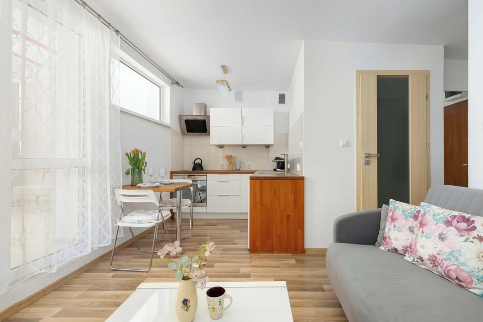 The apartment's entryway leads directly into the main living and dining zone, showcasing a seamless flow. A wooden door with frosted glass panels adds a touch of classic style to the modern interior.