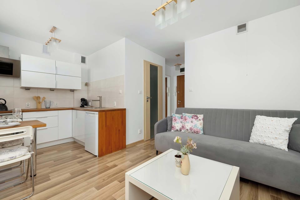 An open-plan view shows the transition from the cozy seating area into the bright kitchen. The layout is designed to maximize the utility of the studio space while keeping it airy.