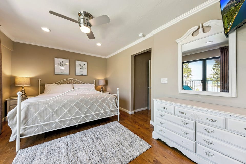 Wake up to gorgeous lake views from your plush bed, where soft bedding and warm wood floors create a cozy retreat. The ceiling fan keeps you cool while natural light floods in, making mornings feel effortless and inviting.
