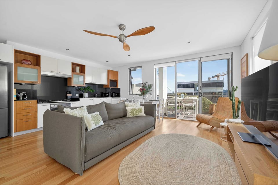 Open plan living space with comfy sofa, dining table for 4 and chef's kitchen, leading onto the balcony with BBQ, alfresco dining table and ocean views of the ocean 