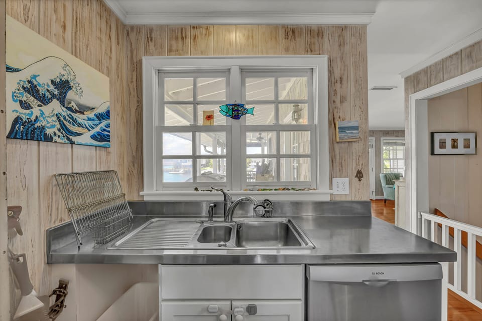 Prepare meals in your coastal-inspired kitchen, where rustic wood walls and ocean artwork create a charming seaside retreat atmosphere.