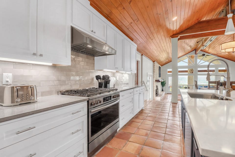 Your spacious gourmet kitchen awaits with gleaming counters, professional appliances, and warm wood ceilings that create the perfect culinary retreat.