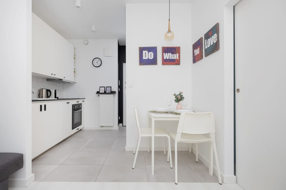 A simple dining setup with a small table and chairs placed next to a clean, white kitchen.