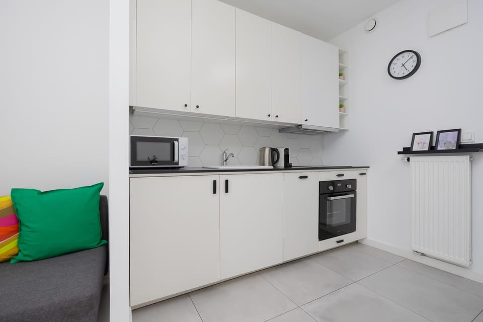 A modern kitchenette with white cabinetry, appliances, and a tidy, uncluttered design.
