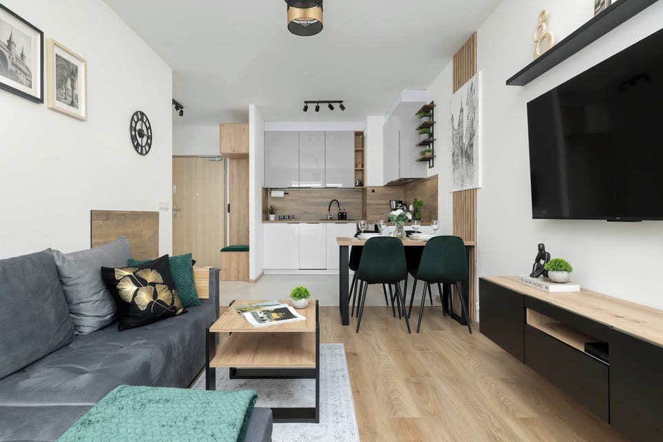 A wide-angle view shows the functional layout of the apartment, including the dining area and the wall-mounted television.
